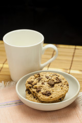 Chocolate chip cookies with coffee cup on wooden.