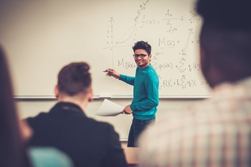 Multinational group of cheerful students taking an active part in a lesson while sitting in a lecture hall.