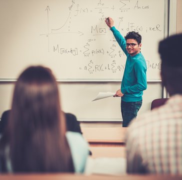 Multinational group of cheerful students taking an active part in a lesson while sitting in a lecture hall.