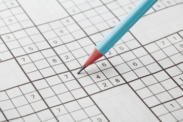 Crossword sudoku and blue pencil for entertainment, popular conundrum