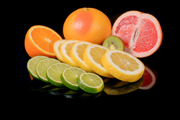 grapefruit, oranges, lime and kiwi isolated on a black background with reflections