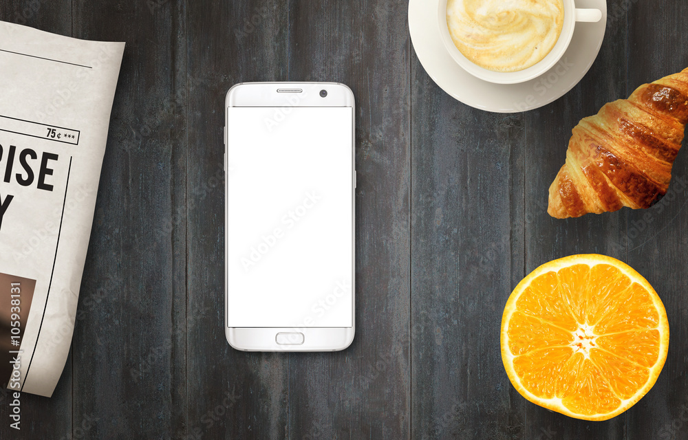 Poster Smart phone with isolated display for mockup on table. Newspapers, coffee, croissant and orange on table. Top view.