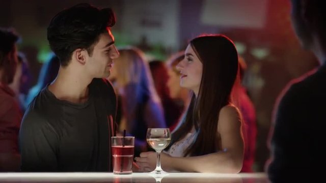 attractive girl at bar in club talking to attractive guy
