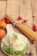 Spaghetti and raw spaghetti on wood background