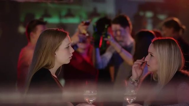 two attractive girls at bar in club talking