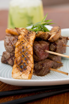 Delicious beef steak cuts on a wooden skewer, cooked rare, served with perfectly grilled mushrooms.