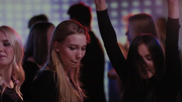 three attractive girls having fun dancing on dancefloor at club