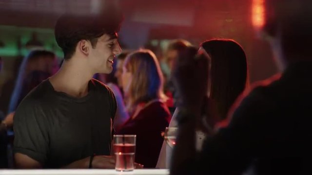 attractive guy talking to attractive girl at bar in club