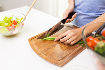 Obraz na płótnie Canvas close up of woman chopping green onion with knife