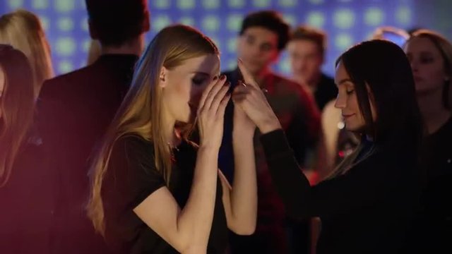 two girls at club dancing close and singing
