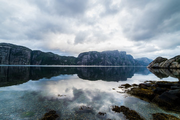 Nature landscape with a view of mountains and clouds reflected in water of fjord in Norway