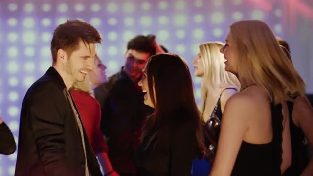 two girls dancing with  one guy at club