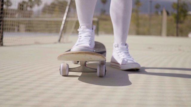 Worms Eye View Of Skater Wearing White Gym Shoes With One Foot On Their Board While Standing In A Ball Court