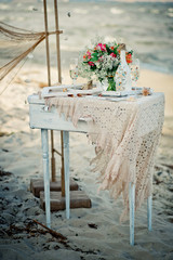 Wedding decor with bottle, glasses, flowers, sea cockleshells and framework for a photo on a ancient suitcase. Decoration of a wedding photoshoot.  Details of a wedding decor in sea style. Vertical 