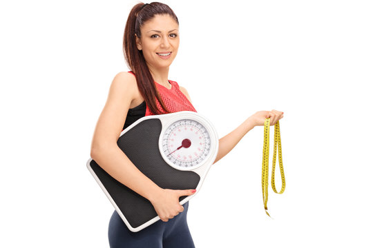 Girl holding weight scale and measuring tape