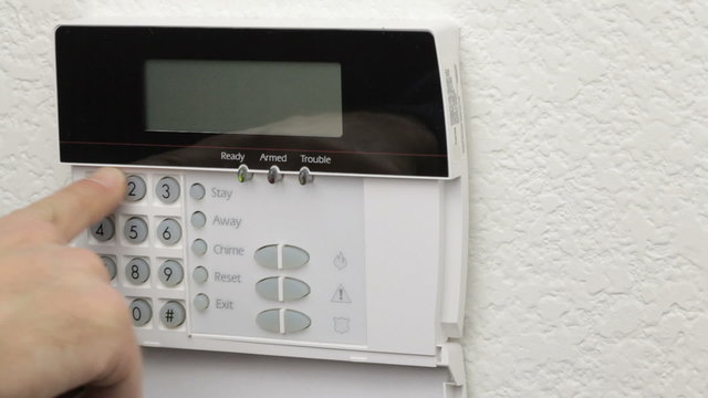 Man arming a home security system using its control panel.