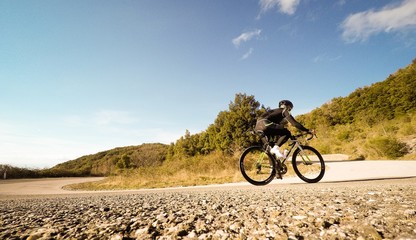 ciclista pedala lungo una strada di montagna in una giorrnata di sole. 