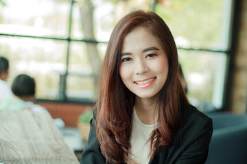 Asian businesswoman smiling while waiting for coffee in the cafe