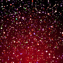 colorful glitter in front of a dark background with a red light from below