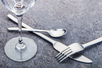 Glänzende Gabel, Teelöffel und Messer aus Edelstahl und ein Weinglas angeordnet auf einer...