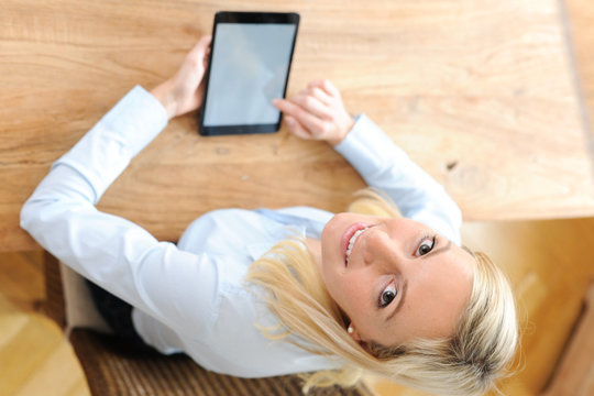 Blonde Frau mit Tablet in der Hand
