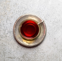 Vintage tea in a mug on a metal saucer on a gray background
