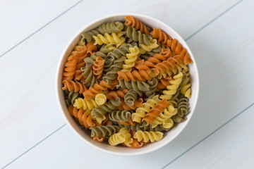 Raw fusilli pasta in a white bowl