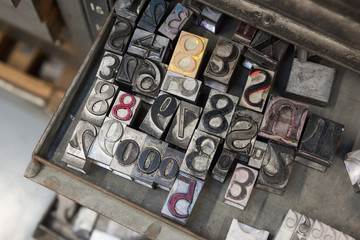Vintage lead letterpress printing blocks against a weathered metal drawer background with bokeh.