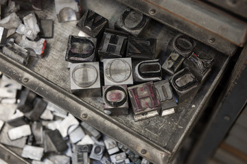 Vintage lead letterpress printing blocks against a weathered metal drawer background with bokeh.