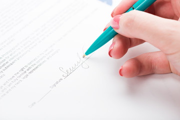 Businesswoman's hand with pen signing a contract.