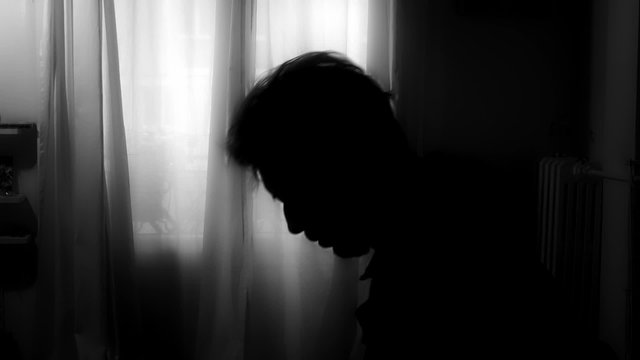 Religious Man Praying Backlit Silhouette. Backlit silhouette of a religious man making a prayer at home in the dark