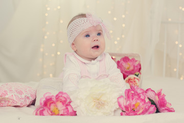 Baby girl is lying on bed with pink flowers