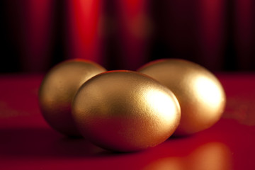 Three golden eggs on red curtain background