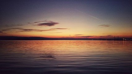 Obraz premium Beautiful sunset over the lake and city lights