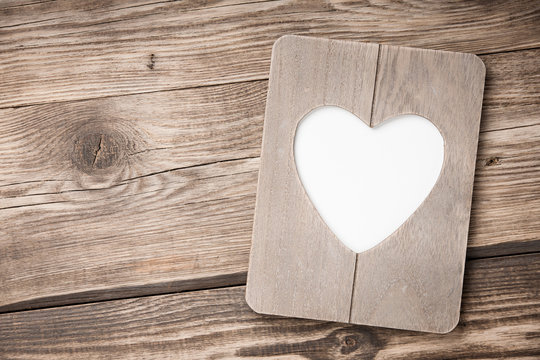 Heart shaped frame on wooden background