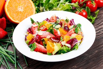 Fresh Orange, strawberry vegetables salad. on wooden table.