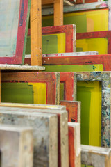 Silk screen printing screens stored in a wooden rack ready for printing.