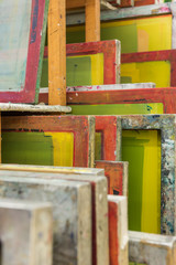 Silk screen printing screens stored in a wooden rack ready for printing.