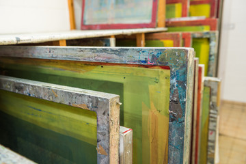 Silk screen printing screens stored in a wooden rack ready for printing.