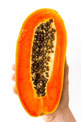 A half ripe papaya with seeds, held in the hand of a young woman, isolated on white.
