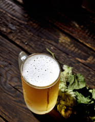 beer in glass, bottle and hops on a wooden background