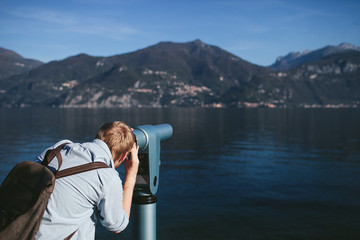 Fototapeta premium man looking in the telescope on the shore of Lake Como