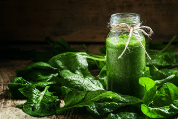 Spinach smoothie in a glass bottle, diet drink, dark wood backgr