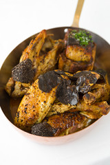 Roasted chicken with foie gras and truffle sauce, topped with sliced truffle, served in a metal pan.