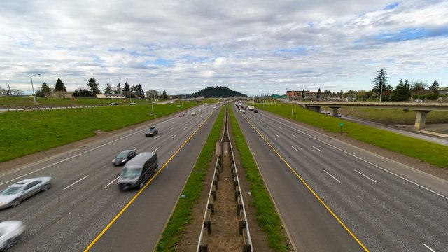 Uhd 4k time lapse of Interstate 205 freeway traffic heading north into Portland Oregon looking at Rocky Butte with white clouds and blue sky 4096x2304