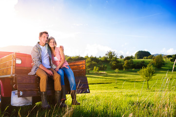 Senior couple sitting in back of red pickup truck © Halfpoint
