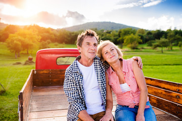 Senior couple sitting in back of red pickup truck © Halfpoint