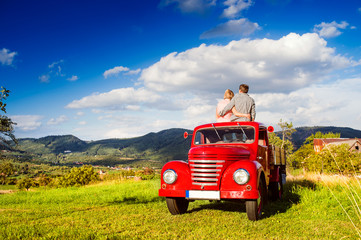 Senior couple sitting in back of red pickup truck