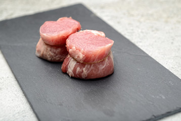 raw fillet medallions on the board of black basalt