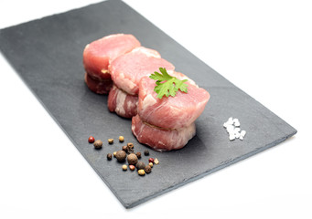 raw fillet medallions on the board of black basalt
